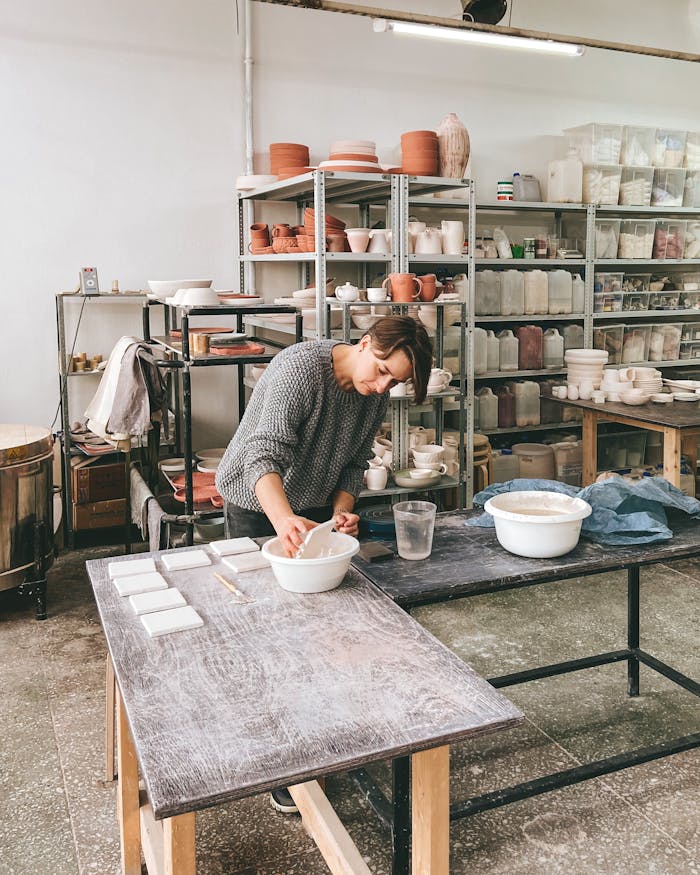 A woman intently crafts ceramics in an industrial-style pottery studio.