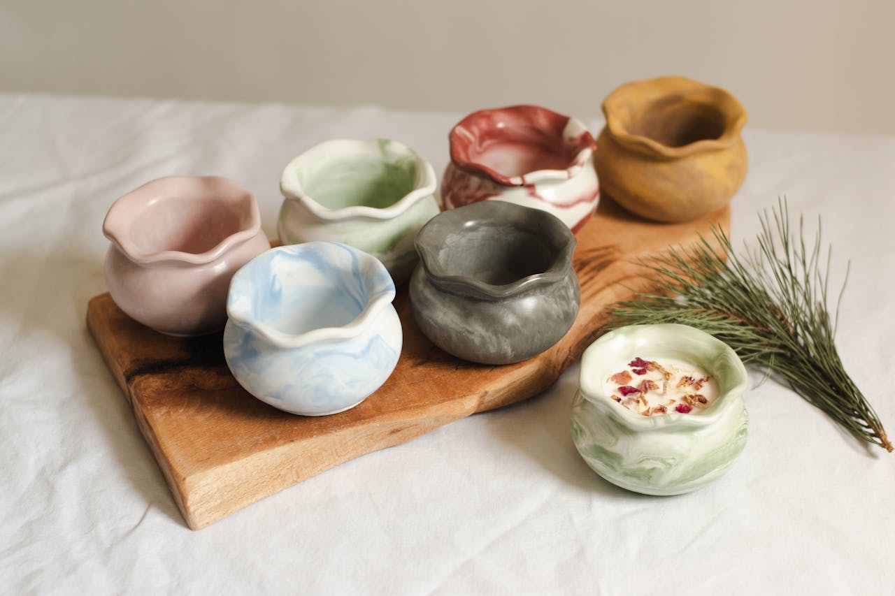 Aesthetic handmade ceramic vases displayed on a wooden board with greenery accent.
