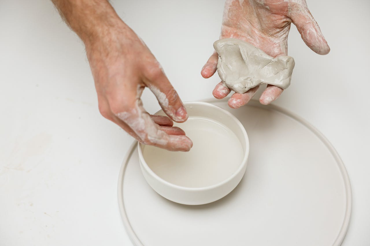 Close-up of hands sculpting clay, showcasing the art and craft of ceramic creation.