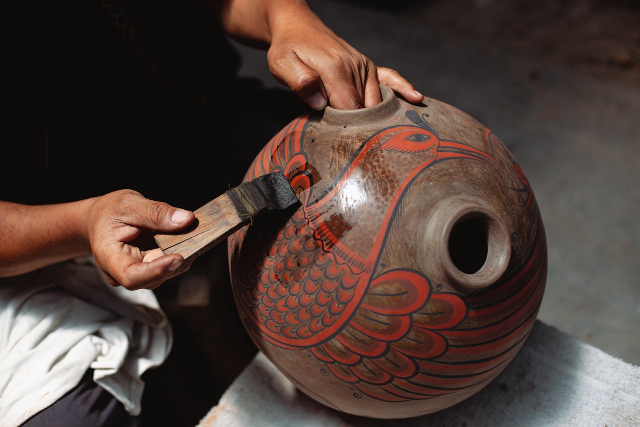 Artisan hand-painting a Mexican ceramic pot, showcasing vibrant traditional craftsmanship.